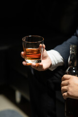 Businessman sitting and holding glass of whiskey..