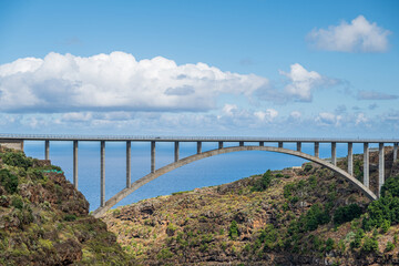 Bridge over a gorge by the sea. Blue water, clouds and a lot of landscape