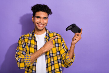 Photo of positive cheerful guy wear plaid yellow shirt pointing finger playstation joystick...