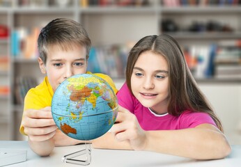 Cute school child in classroom with a globe