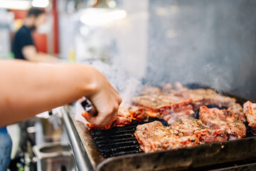 chef cooking pork ribs on grill in kitchen