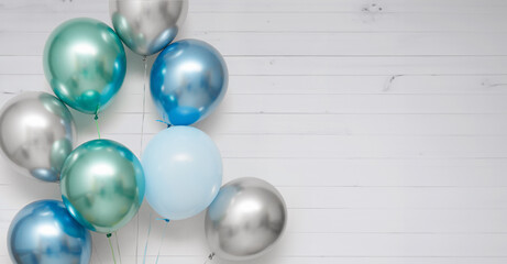 Green, blue, silver balloons on a wooden light background.