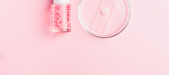 Glass petri dish and liquid cosmetic product with pink molecules. Cosmetic laboratory concept. Banner. Copy space