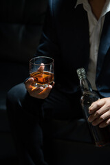Businessman sitting and holding glass of whiskey..