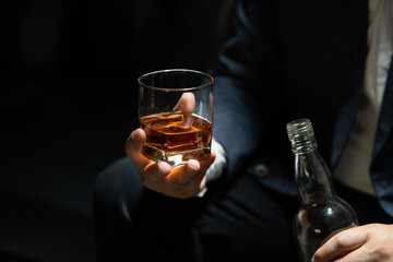 Businessman sitting and holding glass of whiskey..