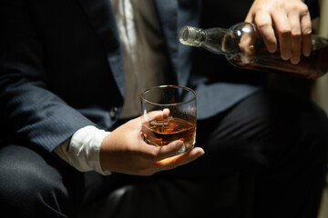 Businessman sitting and holding glass of whiskey..