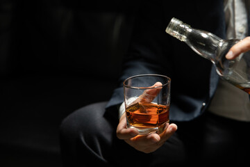 Businessman sitting and holding glass of whiskey..