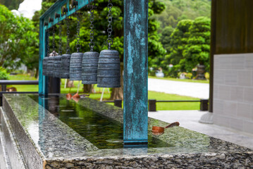 Fototapeta premium Close up of the water tribute pond at Tsz Shan Monastery in Hong Kong with wooden water spoon and chimes