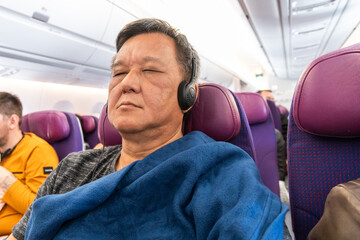 Passenger cover himself with wool blanket provided by airline during longhaul flight for warm and comfort