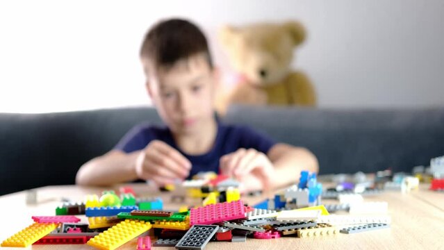 child, kid plays with colored plastic parts of the constructor, creates buildings, equipment, transport, the concept of the development of creativity, fine motor skills, patience and perseverance