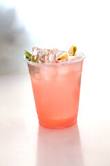 Pink rose lemonade placed on top of ice cubes with lemon slice and fresh mint.