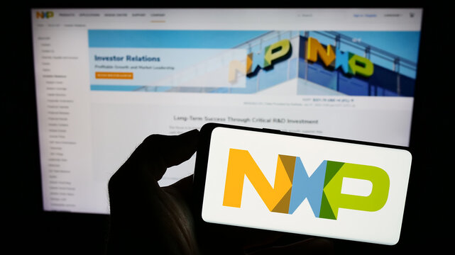 Stuttgart, Germany - 07-28-2023: Person holding smartphone with logo of Dutch company NXP Semiconductors N.V. on screen in front of website. Focus on phone display.