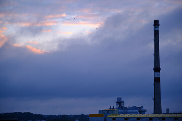 Fototapeta premium Industrial pipe on the background of blue thick clouds. Evening time