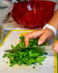 The cook's hands cut the greens finely and sort them