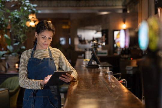 Waitress in a bar using a digital tablet for accounting