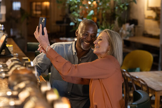 Senior couple on a date in a wine bar taking a selfie together on a cell phone