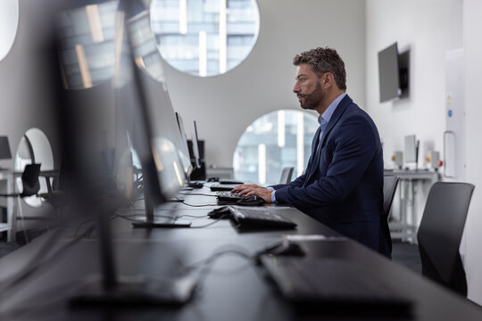 Male business executive working in an empty office on a desktop computer