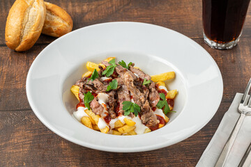 Turkish food Cokertme Kebab. Kebab made with thinly sliced beef steak on french fries and yoghurt