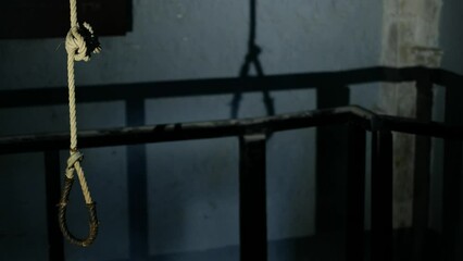 An authentic hanging rope in a real hanging chamber. the rope has a significant shadow on the bare walls, something that enhances the creepy feeling of the place. a 4K video clip.