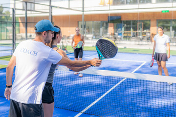 Empowering padel tennis training as a coach skillfully instructs a young woman on the outdoor court, fostering skill development and a positive learning environment