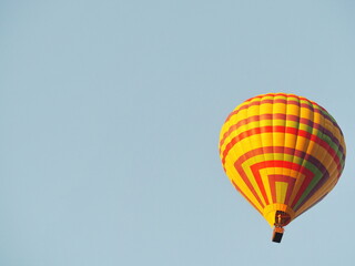 Yellow balloon against the sky in Laos, Vang Vieng. Hot air balloons with passengers flying over blue sky background. The balloons have a reddish yellow pattern. Tourists having fun and taking picture