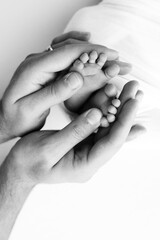 The palms of the father, the mother are holding the foot of the newborn baby on white background.