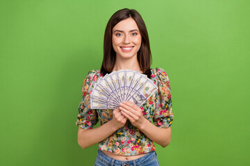 Portrait of gorgeous successful girl toothy smile hands hold dollar banknotes bills isolated on green color background