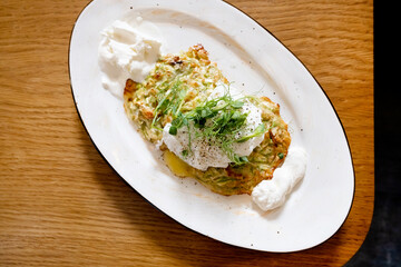 Zucchini fritters, vegetarian zucchini pancakes, served with poached egg and sour cream.