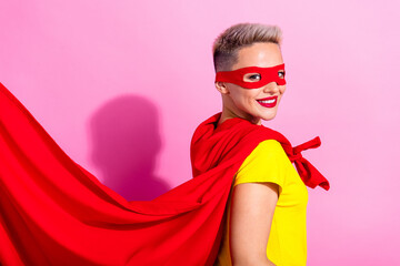 Profile portrait of satisfied pretty super girl beaming smile wear red cape mask isolated on pink...