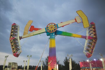 View of colorful summer carnival ride at fun fair during dusk