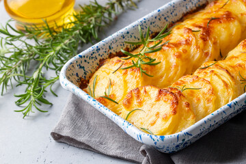 Potato gratin - graten (baked potatoes with cream and cheese) with rosemary and forks (Turkish name; Kremali patates)