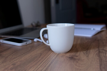 a cup of coffee close-up on the background of a laptop and a notepad with a pen. coffee break composition during work.