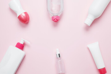 Cosmetic beauty products on pink background. Bottles and tubes with branding mock up. Skin care and beauty concept. Top view, flat lay, copy space