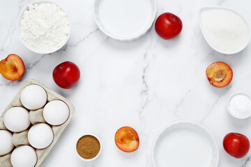Ingredients for making classic cake pie with plums on white background. Concept homemade food, seasonal pastries. Top view, copy space