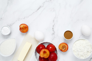 Ingredients for making classic cake pie with plums on white background. Concept homemade food, seasonal pastries. Top view, copy space