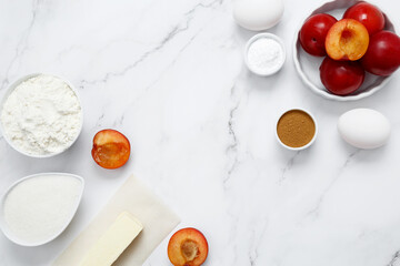 Ingredients for making classic cake pie with plums on white background. Concept homemade food, seasonal pastries. Top view, copy space