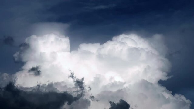 Time-lapse footage of huge white cumulonimbus cloud expanding and rising up in the blue sky. Cloudscape