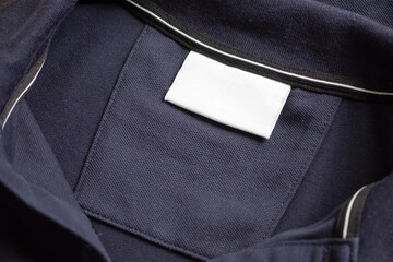 Blank white laundry care clothes label on black shirt fabric texture background