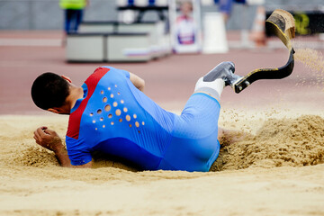 para-athlete long jump, landing in sand at athletics competition, summer sports games