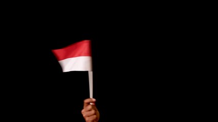 Male hand holding Indonesia flag, waving it and making a circular pattern over the dark background