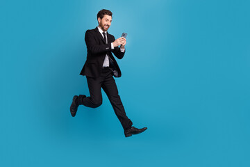 Fototapeta na wymiar Full size body photo of jumping crazy running entrepreneur agent hold his phone receive crazy offer isolated on blue color background