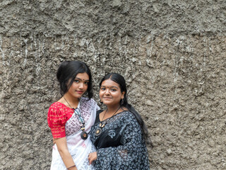 South asian young sisters in front of an abstract background wearing traditional clothes 