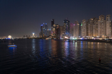 Obraz premium View of the skyline of Marina dubai with business and residential towers and the Marina beach illuminated at night, Dubai, UAE