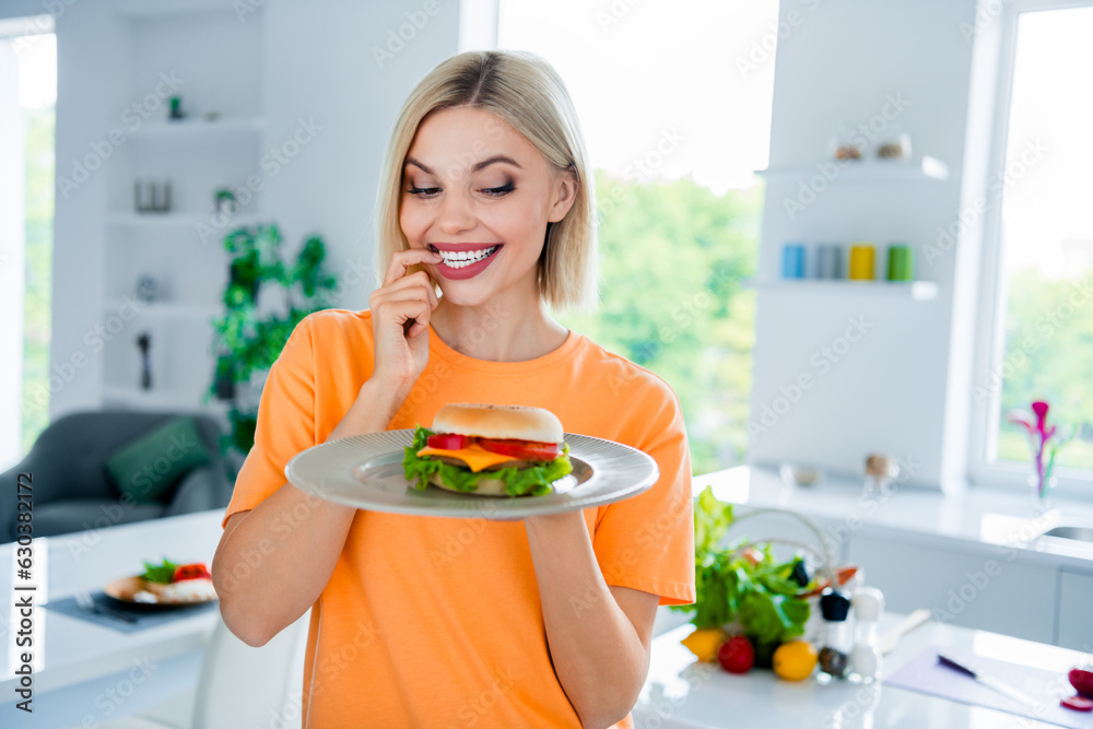 Sticker photo of excited girl feel curious eating junk food delicious burger in white dining room