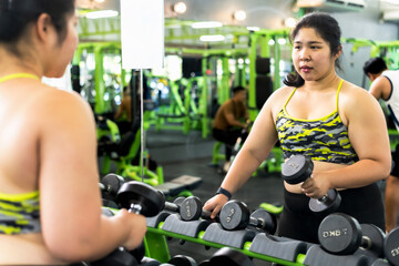 Fototapeta na wymiar Fat sport woman doing exercise in gym, oversized woman work out in fitness