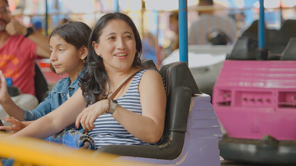 The family drives a bumper car at the amusement park, enjoying the ride.