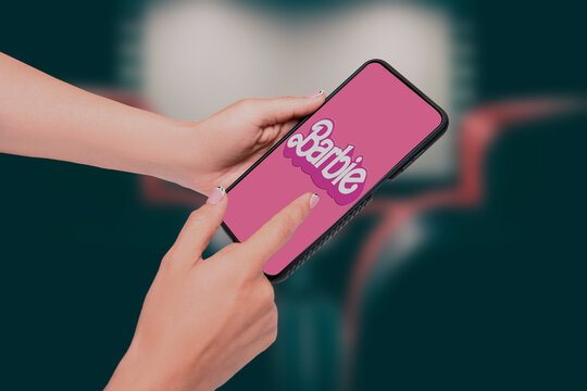 The Barbie logo with a pink background on the screen of a smartphone in the cinema
