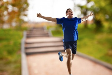 Cheerful and successful sporty man jogging outdoor