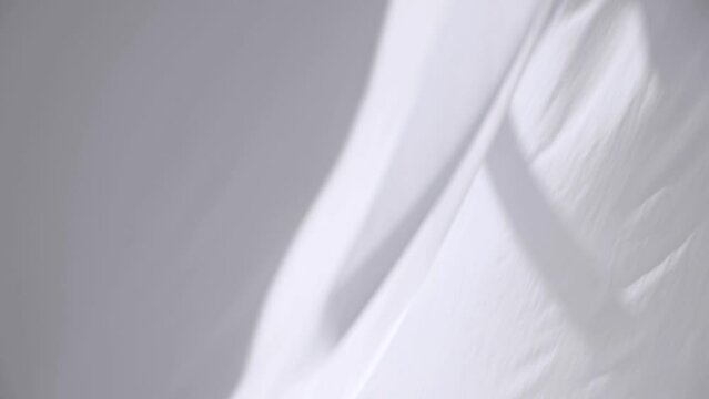 White transparent fabric flutters in the wind. Long white curtains in a bright studio. slow motion