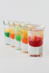 Glasses filled with vodka, each topped with passion fruit, strawberry, apple, and mango